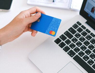 female hand holding credit card over laptop