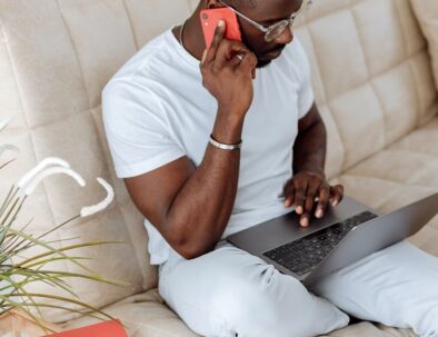 man on couch with laptop and smartphone